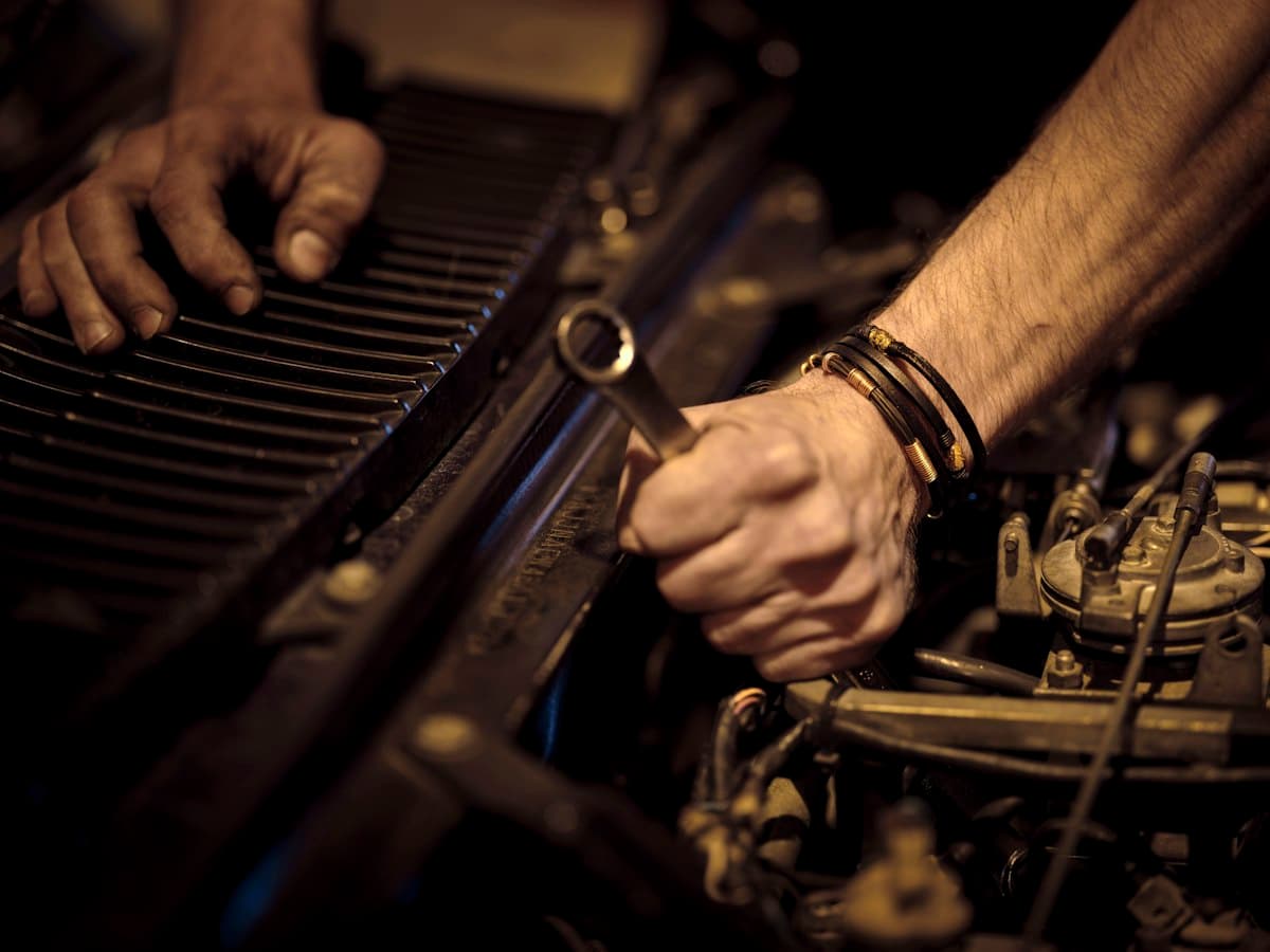 Mechanic's hands adjusting a component inside an engine bay