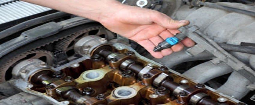 Fuel injector being inspected next to an open engine's camshafts